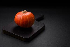 Beautiful fresh round pumpkins in orange color on a dark concrete background photo