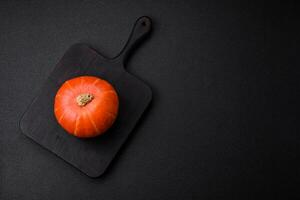 Beautiful fresh round pumpkins in orange color on a dark concrete background photo