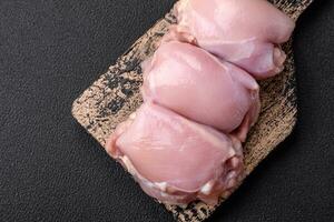 Fresh raw chicken thigh fillets with salt, spices and herbs photo