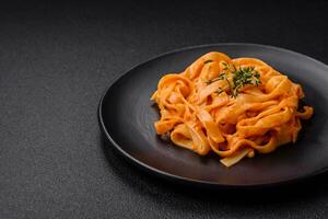 Delicious fresh pasta with pesto sauce, salt, spices and herbs on a ceramic plate photo