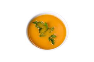 Delicious fresh pumpkin puree soup decorated with parsley in a white plate photo