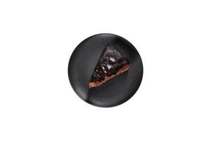 A piece of fresh delicious cake with nuts and chocolate on a black plate photo