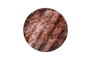 Delicious fresh juicy beef steak with spices and herbs on a dark concrete background photo