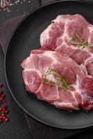 Fresh juicy pork steaks with salt, spices and herbs photo