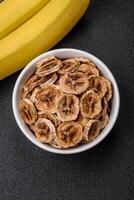 Round slices of sweet banana on a dark concrete background photo