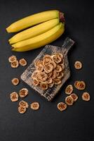 Round slices of sweet banana on a dark concrete background photo