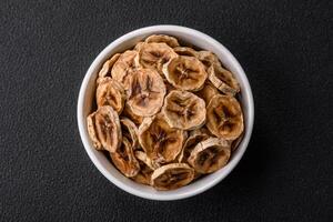 Round slices of sweet banana on a dark concrete background photo