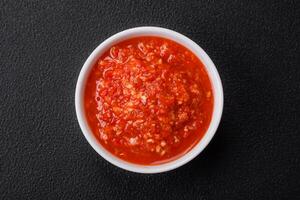 Delicious hot spicy red sauce with salt and spices in a ceramic bowl photo