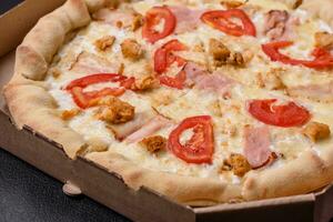 Delicious hot pizza with chicken, tomatoes, cheese and bacon, with salt and spices photo