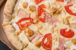 Delicious hot pizza with chicken, tomatoes, cheese and bacon, with salt and spices photo