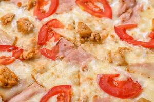 Delicious hot pizza with chicken, tomatoes, cheese and bacon, with salt and spices photo