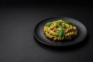 Delicious fresh pasta with green pesto sauce with basil photo