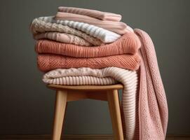 Stack of clean freshly laundered, neatly folded womens clothes on wooden table. Pile of shirts, dresses and sweaters on the table, white wall background. Created with Generative AI technology. photo