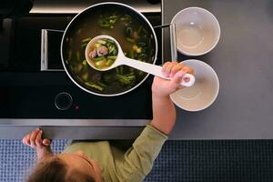 The girl serves the soup with a ladle. photo