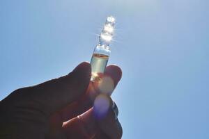 Ampoule in hand against the blue sky. photo