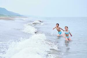 un chico y un niña son teniendo divertido jugando en el mar. foto