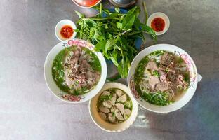pho bo vietnamita sopa con carne de vaca y arroz tallarines en un metal mesa, real escena en local restaurante foto