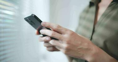 stänga upp skott av ung vuxen stående i kontor och skriver meddelande via smartphone. video
