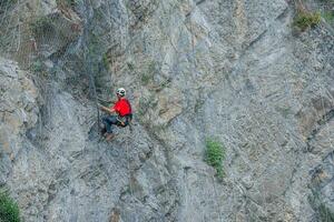 Climber placing safety nets to avoid falling rocks photo