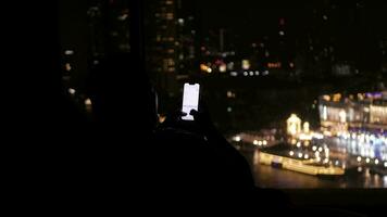 asian man sit on coach near giant window with view of river in night time video