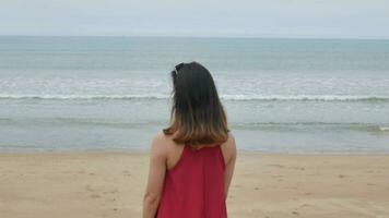 un joven asiático mujer caminar en el playa y relajarse mientras en fiesta vacaciones video