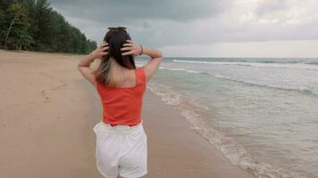 slowmotion of young adult lady relaxing walking on the beach with sea wave in video