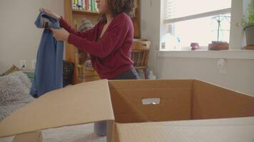 joven latín mujer embalaje ropa en caja a dar a caridad video