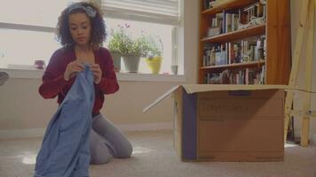 Young Hispanic Woman Packing Clothes to Give to Charity video
