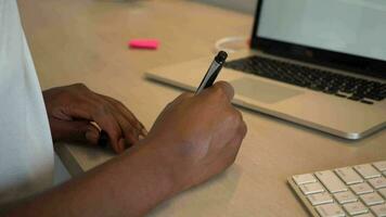 Black businesswoman writing note on post-it, setting reminder, writing to do list video