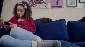 kvinna får bekväm på soffa och utseende på social media på henne telefon video