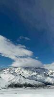 vertical vídeo de aéreo ver zumbido volador terminado hermosa blanco Nevado montañas video