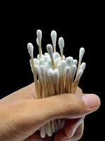 Wooden cotton swabs holding with the male hand for the ears with black background photo