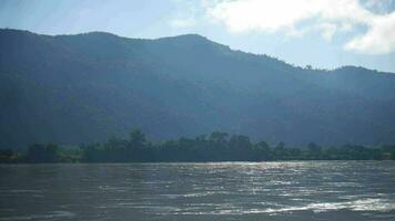 natural paisaje terminado un corriente corriendo a río con bosque y montaña, el mekong río tiene fluido agua, Mañana niebla en denso tropical selva video