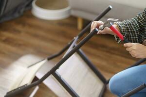 Asian Woman self repairs furniture renovation using equipment to diy repairing furniture sitting on the floor at home photo