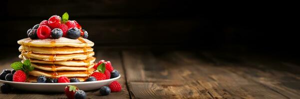 Stack of pancakes with berries on rustic table background with empty space for text photo