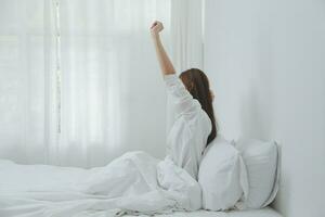 mujer estirándose en la cama después de despertarse foto