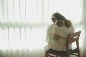 silhouette of woman sitting on the bed beside the windows with sunlight in the morning photo