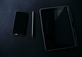 Open laptop with digital tablet and white smartphone. All with isolated screen on old wooden desk. photo