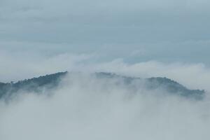 Mountain range with visible silhouettes through the morning blue fog. photo