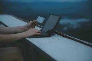 online payment, young woman holding credit card and typing on laptop photo