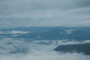 Mountain range with visible silhouettes through the morning blue fog. photo