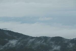 Mountain range with visible silhouettes through the morning blue fog. photo