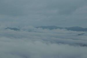 Mountain range with visible silhouettes through the morning blue fog. photo