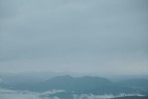 Mountain range with visible silhouettes through the morning blue fog. photo