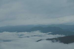 Mountain range with visible silhouettes through the morning blue fog. photo