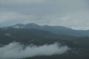 Mountain range with visible silhouettes through the morning blue fog. photo