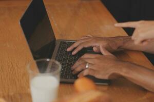 Handsome man sitting near his wife at kitchen. Family couple see social media, surf the web while sitting at kitchen table with generic laptop. Couple working with laptop at home photo