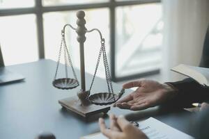 Business and lawyers discussing contract papers with brass scale on desk in office. Law, legal services, advice, justice and law concept picture with film grain effect photo