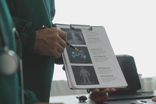 Multiracial team of doctors discussing a patient standing grouped in the foyer looking at a tablet computer, close up view photo