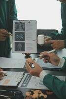 Multiracial team of doctors discussing a patient standing grouped in the foyer looking at a tablet computer, close up view photo